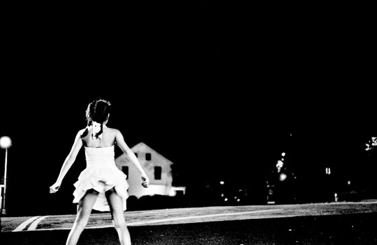 Girl in braids dancing in a white dress during a full moon